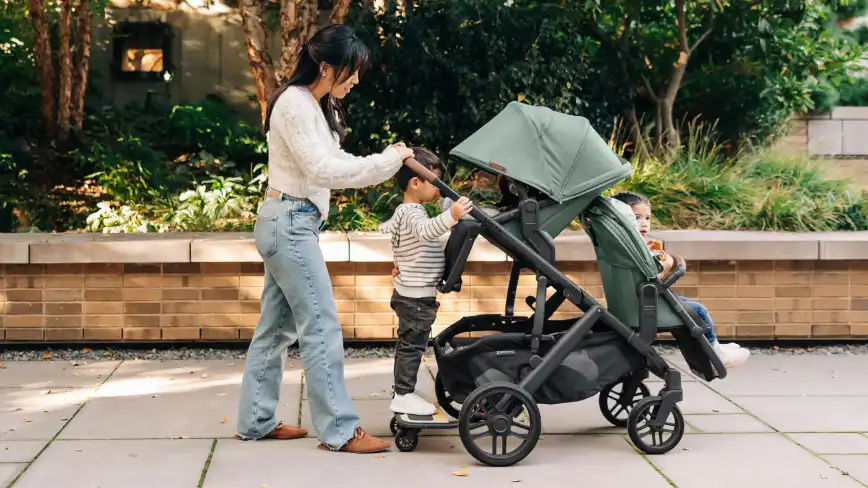 Parent pushing three children, including one of the canopies extended
